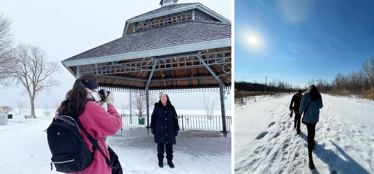 Two women standing in the snow, one being photographed by the other.