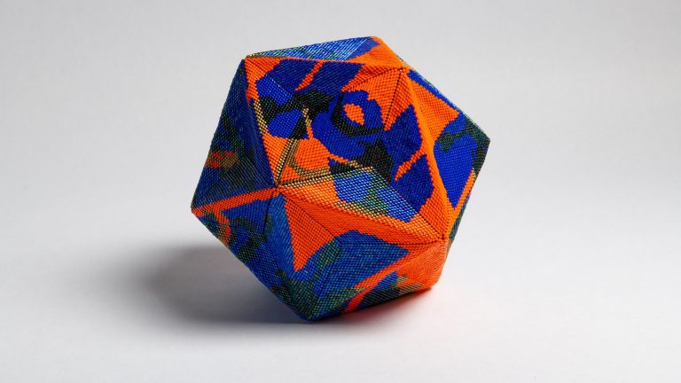 An artwork which is a hexagonal sculpture made of bead work.
