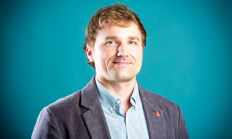 Marek Majewski: “We’re very interested in the efficient and sensitive detection of disease biomarkers.” Smiling man with short(ish) blonde hair and a checkered collared shirt.
