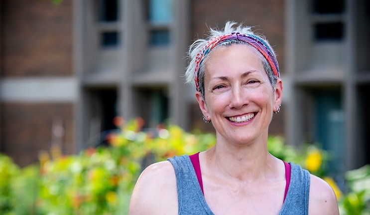 Smiling woman with short, blonde hair and wearing a bandana and singlet.