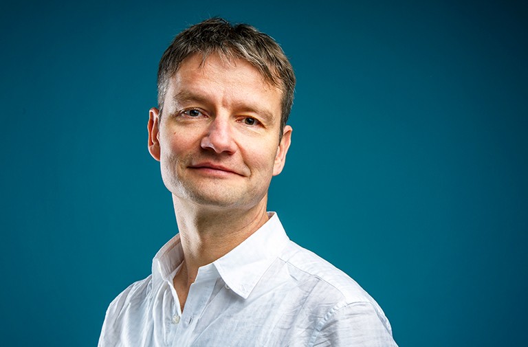 Man with short, blonde hair and wearing a white shirt