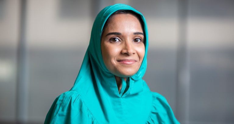 A smiling Muslim woman wearing a turquoise hijab