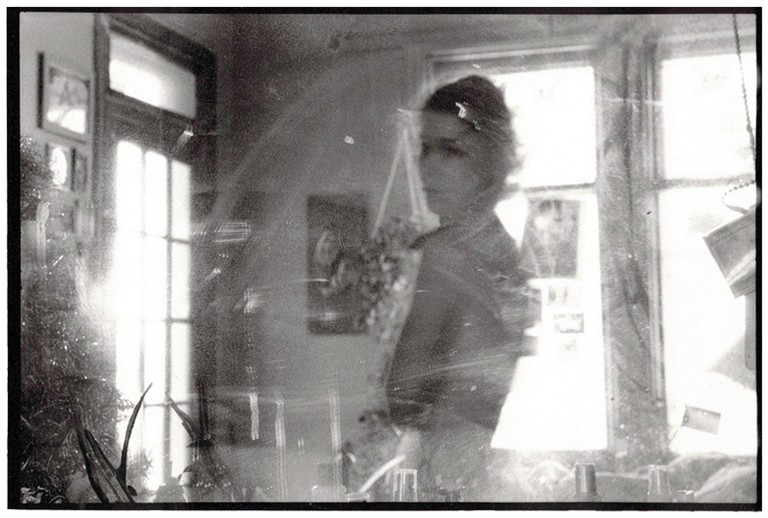 A blurred black and white photograph of a woman standing in a salon and looking to the left of the photographer.