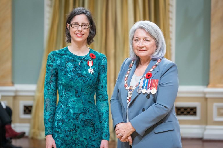 Two women in formal attire pose for a photo at an awards ceremony. 