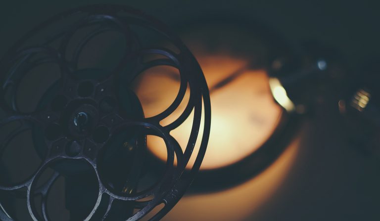 A close up of an old-fashioned film real with a golden light in the background.