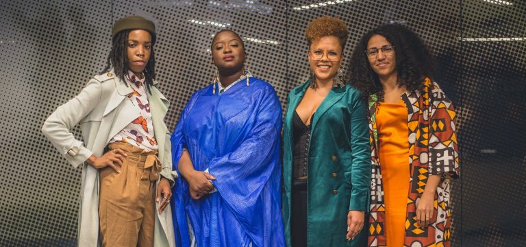 Four women standing together and smiling for the camera.