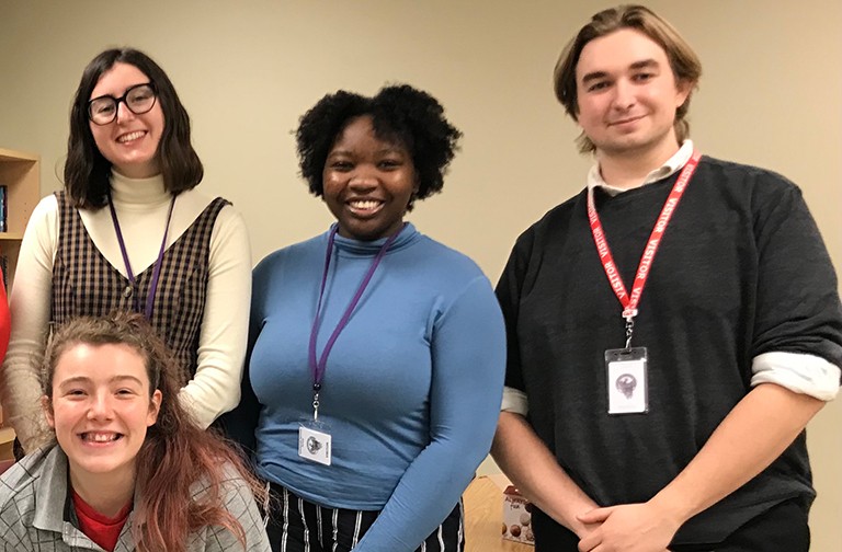 A group of four young men and women smiling for the camera.