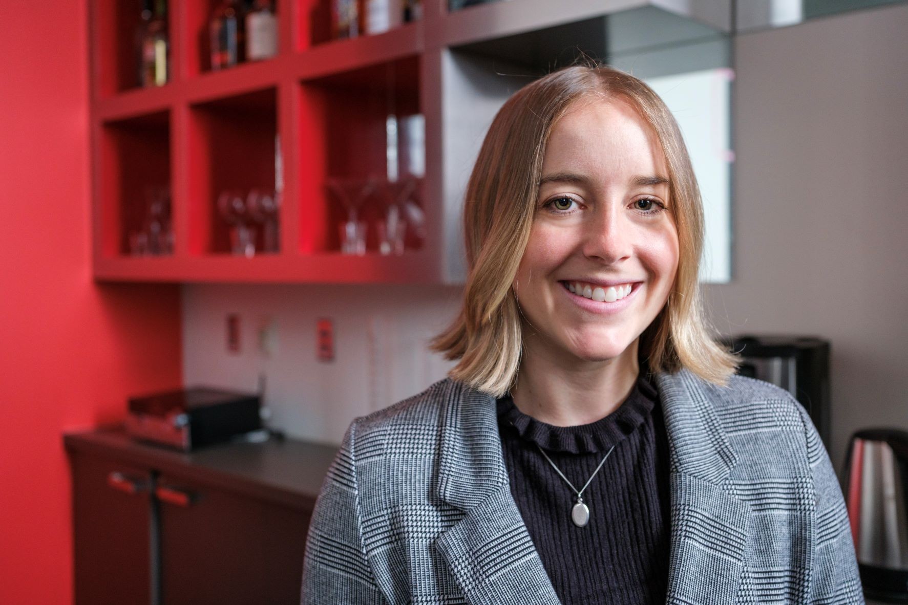 Charlotte Corran (young, smiling woman with shoulder-length blonde hair) sitting at a table