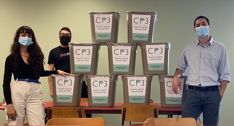 CP3 coordinators Wanda Stamford and Felix Beaudry, with CP3 collection bins at Studio Artefact. Three people all wearing masks, one woman and two men, standing beside bins with the lettering, "CP3, Plastic waste collection" on them.