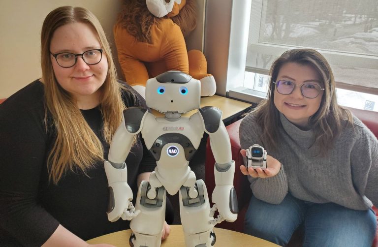 Anna-Elisabeth Baumann poses with Elizabeth Goldman and robots Nao and Cozmo