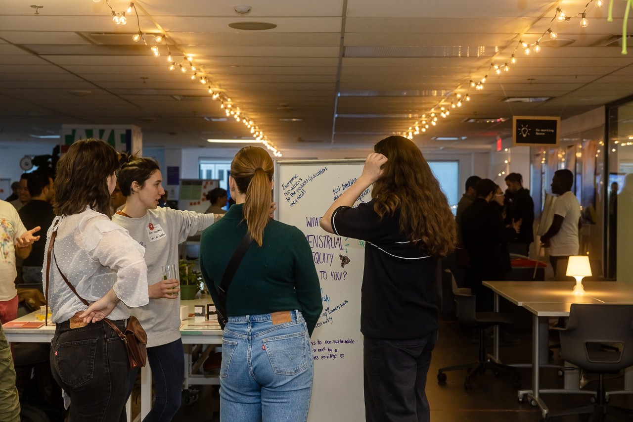 Julie Hamel: “I think this reflects the university’s values and its mission to drive positive change in society.” Three students sitting and talking in front of a screen.