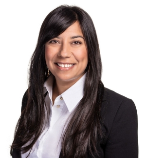 Smiling woman with long, dark brown hair, wearing a collar shirt and a black blazer