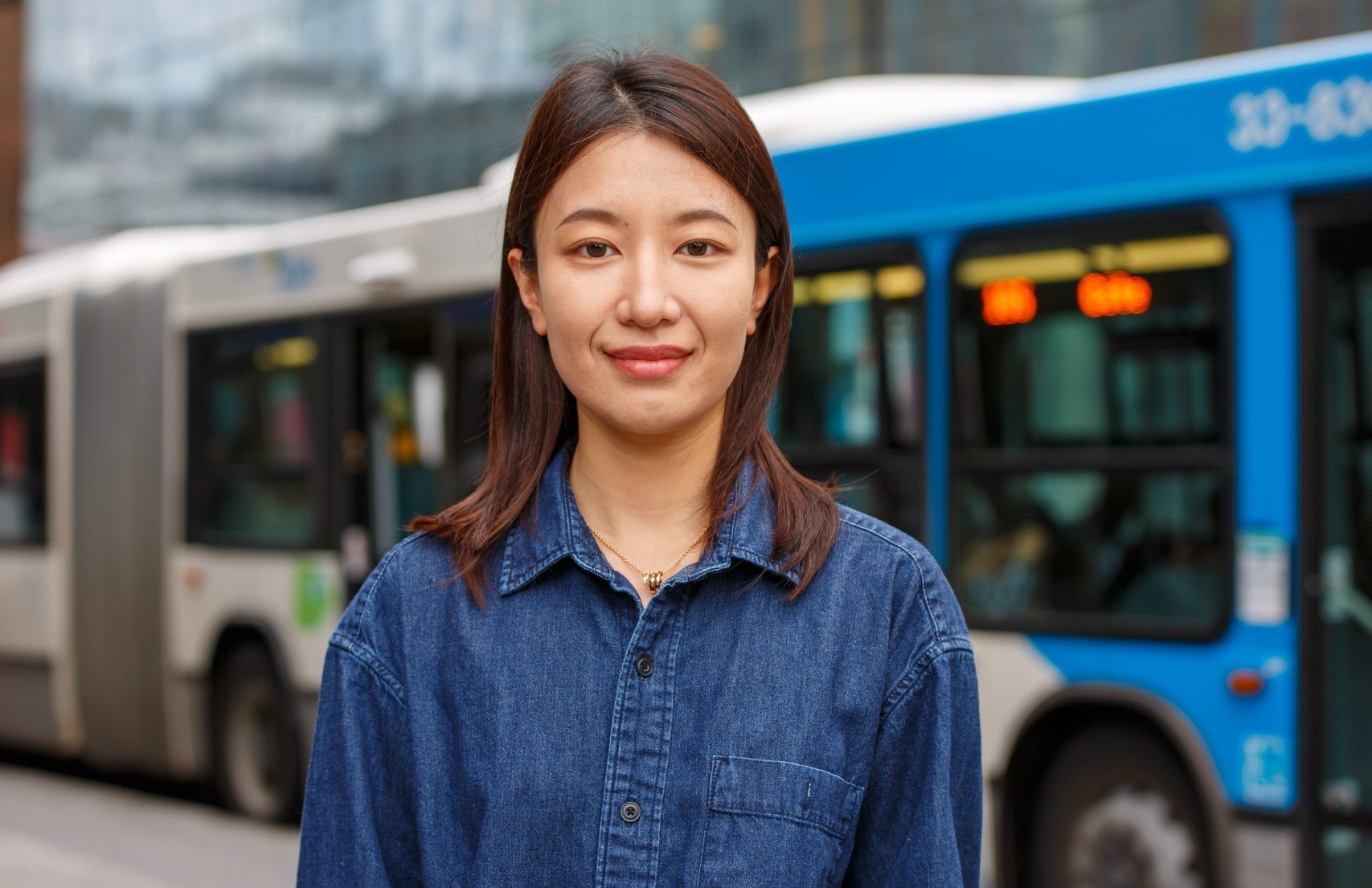 Xuelin Tian wears a blue shirt standing in front of a Montreal city bus
