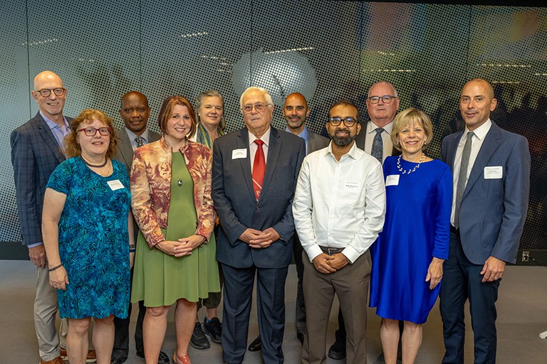 A group of men and women standing together in an indoor setting and smiling for the camera