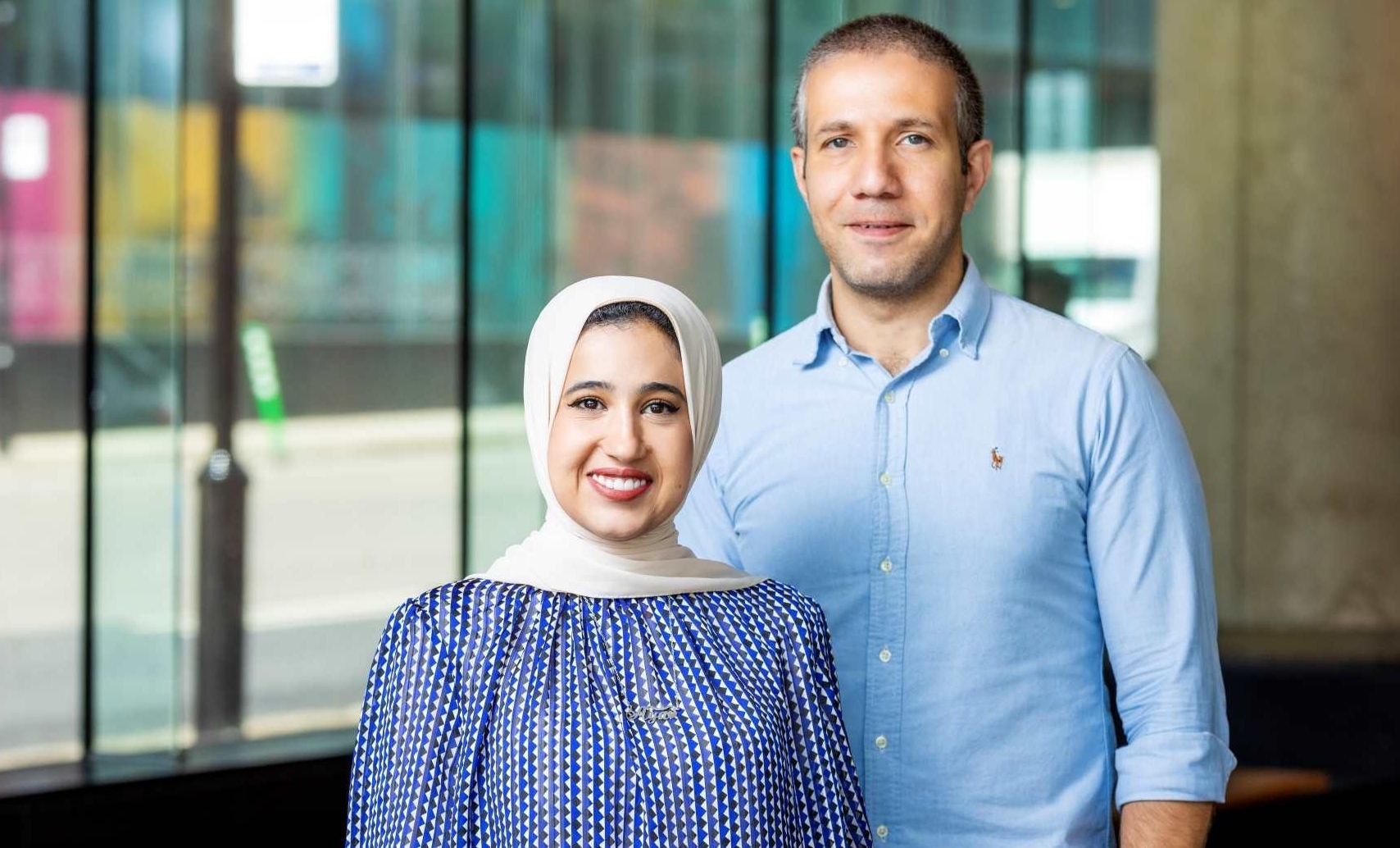 Aya Doma and Mohamed Ouf stand in front of a ground-floor window at Concordia University
