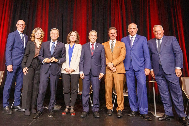 A group of men and women standing together on a stage and smiling for the camera.