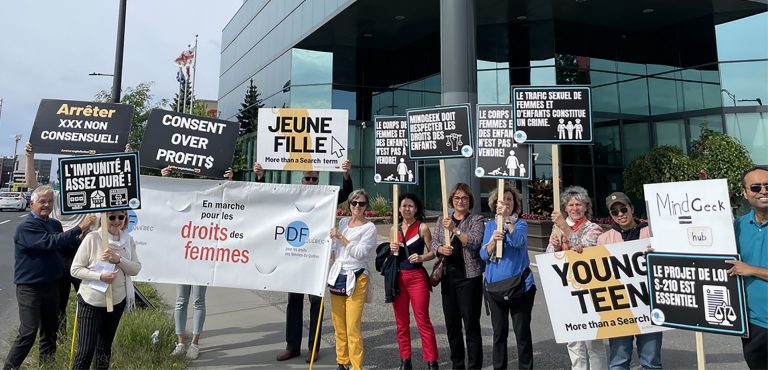 A group of diverse protestors standing on a grass verge in front of a sky scraper with signs that say things like, "Jeune fille: more than a search term," and "Consent over profits."