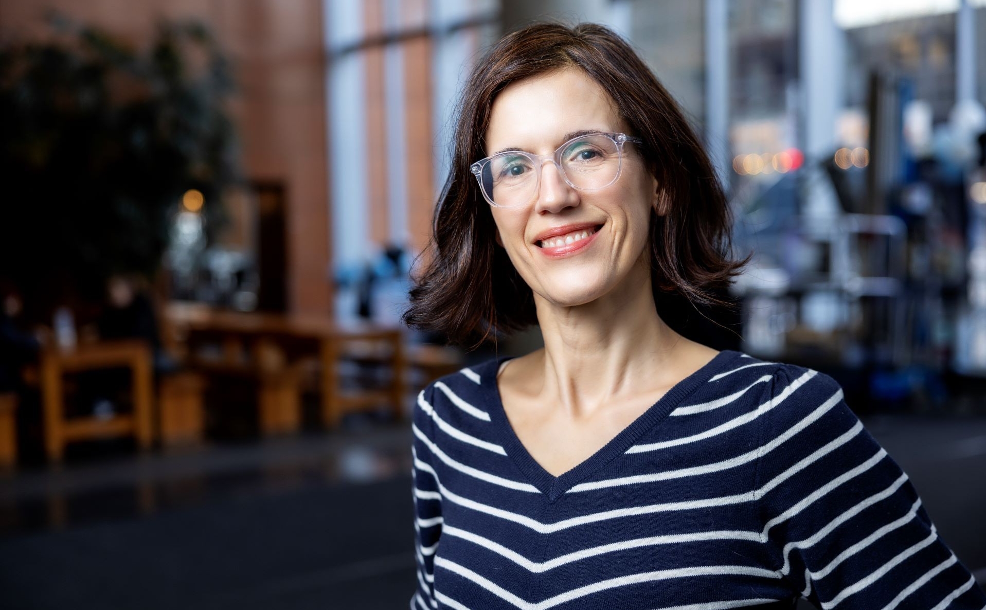 Claudine Mangen has shoulder length dark hair and wears a horizontally striped blue and white shirt