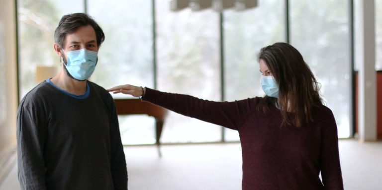 A man and a woman wearing face masks practice social distancing