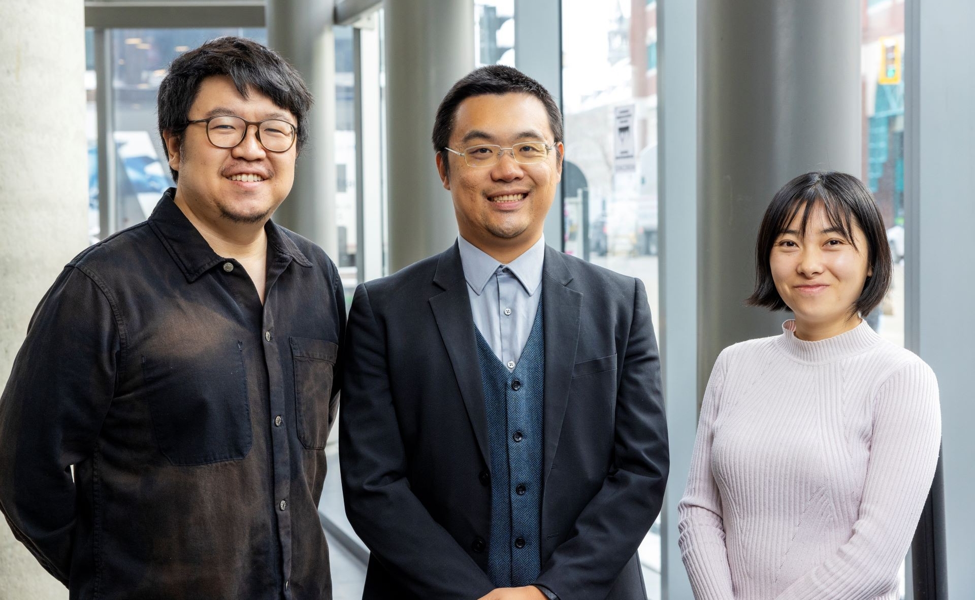 PhD student Hang Du wears a black shirt, Prof. Jun Yan has glasses, a black jacket over a blue shirt and waistcoat and PhD student Juanwei Chen wears a high collar white crew neck sweater.