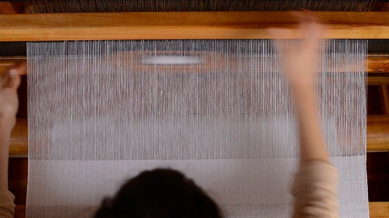 Hands using a weaving loom