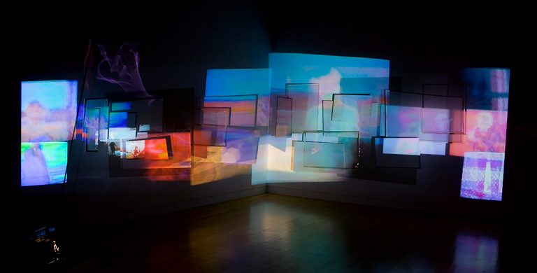 An artist's installation of an array of colourful screens in a darkened room