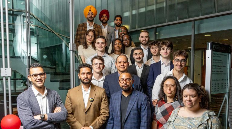 A diverse group of people standing together on a stairwell and smiling for the camera.
