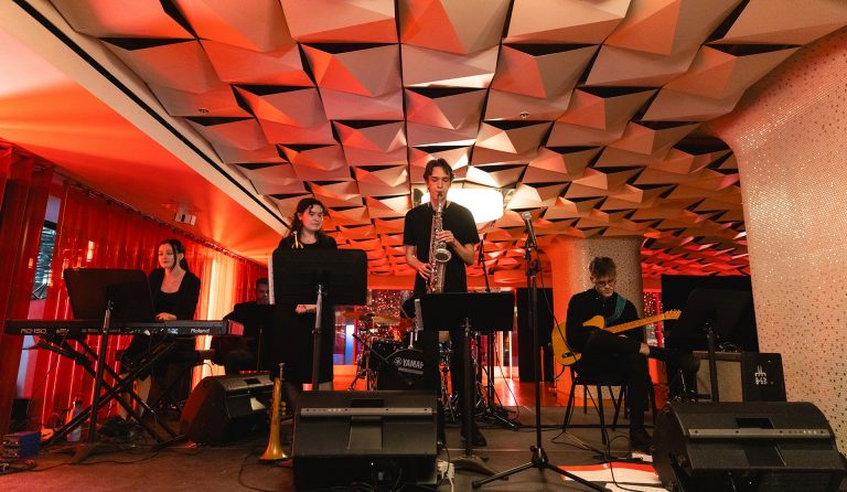 Young people performing jazz music on an orange-lit stage