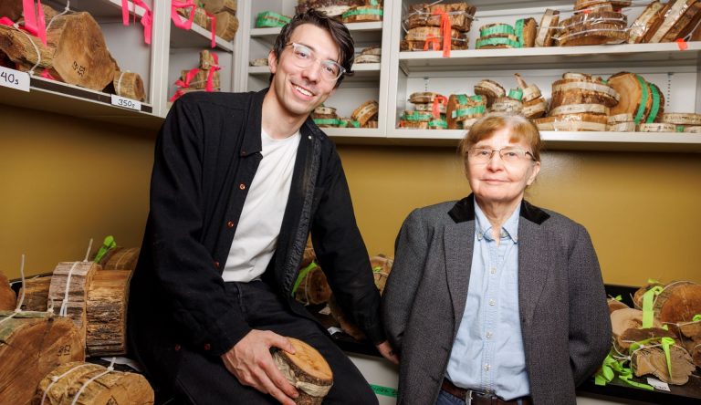 A man and a woman in a room full of tree core samples