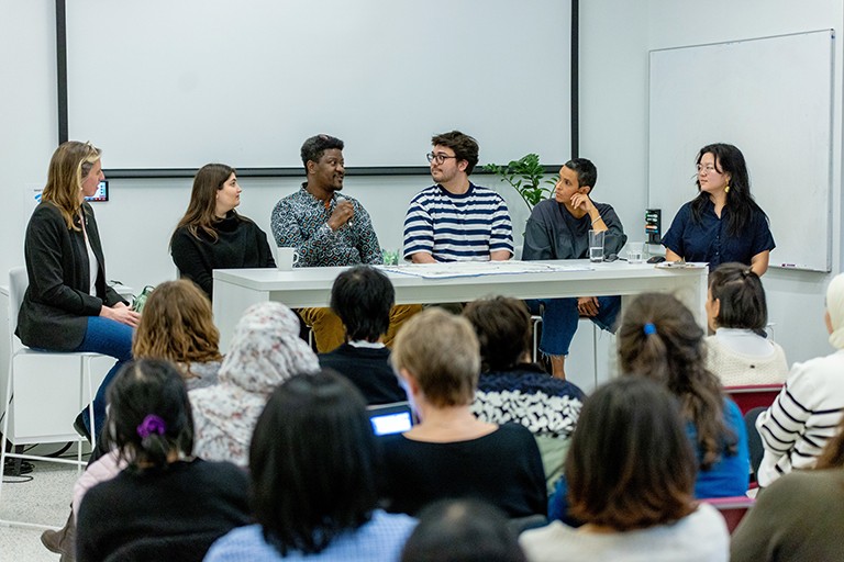 The SHIFT internship showcase highlighted this program that has funded over 310 student internships at grassroots community organizations across Montreal. A panel of diverse people seated at a long table and talking in front of an audience