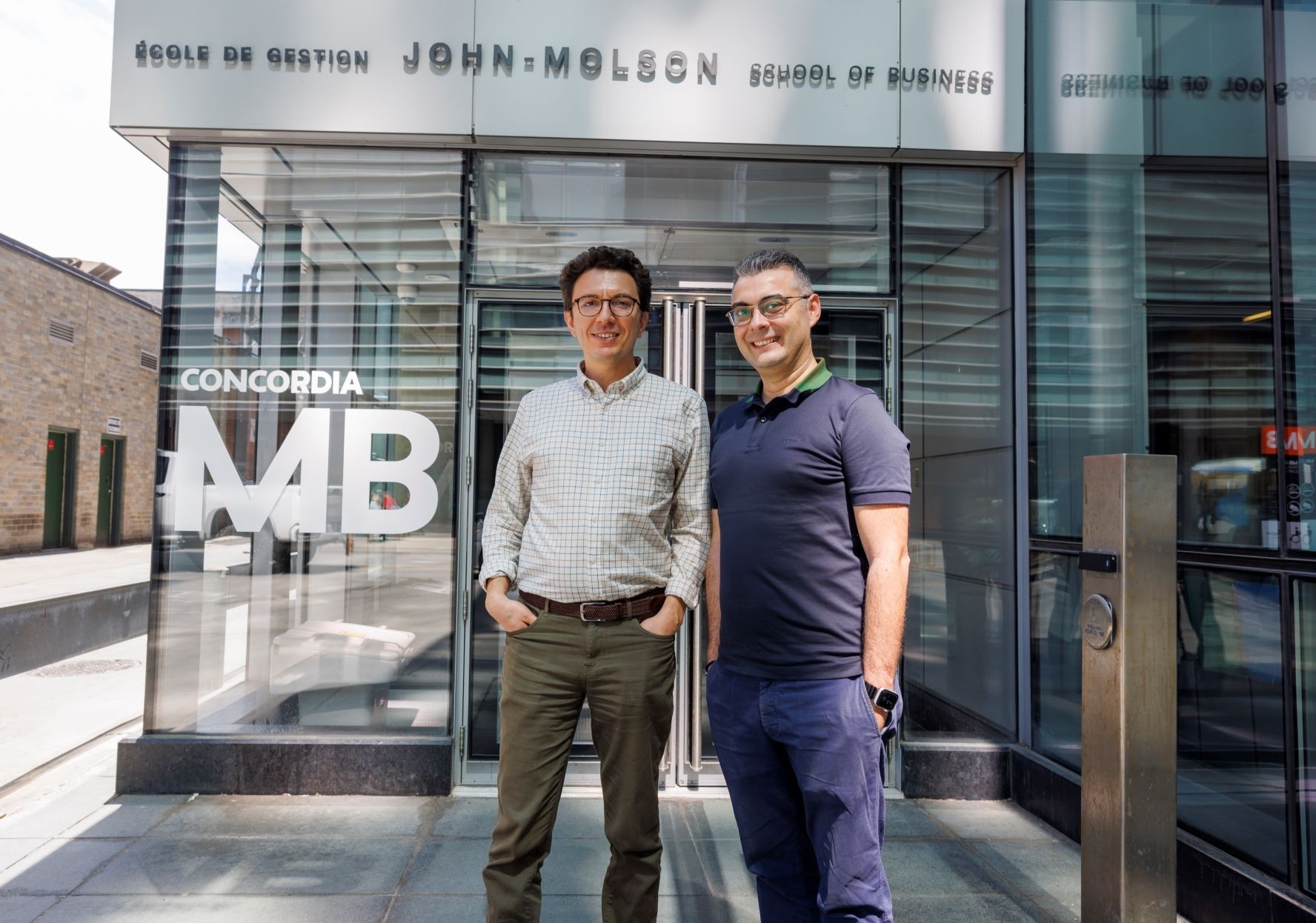 Two men stand outside the John Molson School of Business