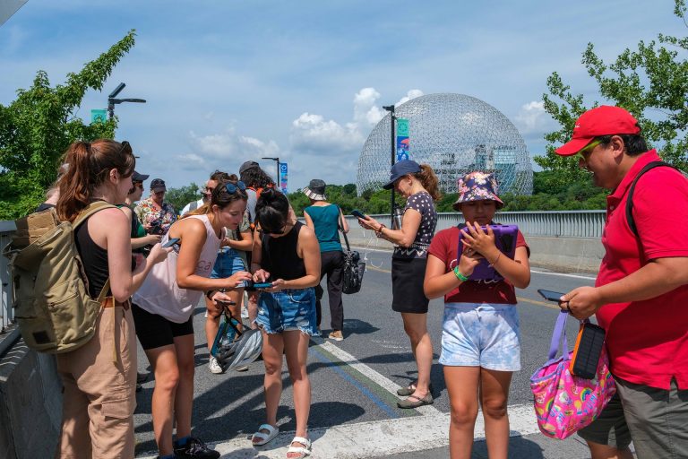 A group of people in an urban setting, talking to each other and looking at mobile phones