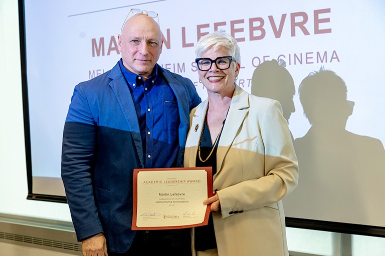 A man and woman at an award ceremony, smiling for the camera.