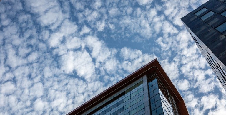 City buildings and a sky with puffy clouds seen from below