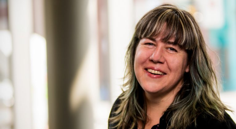A smiling woman with long dark-blonde hair. 