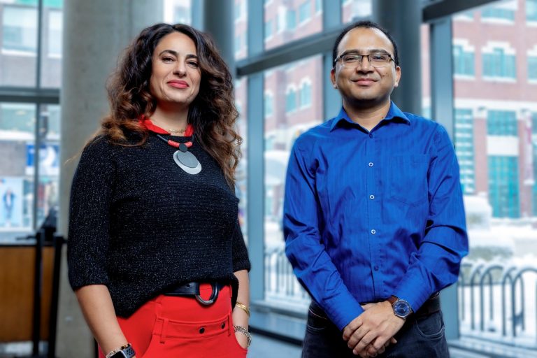 A woman in a black shirt and red skirt stands next to a man in a blue shirt and black pants