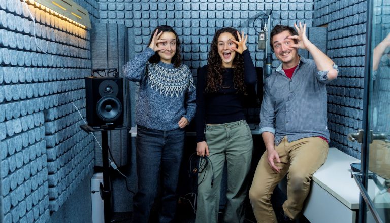 Three researchers in an audiovisual lab jokingly hold their eyes open 