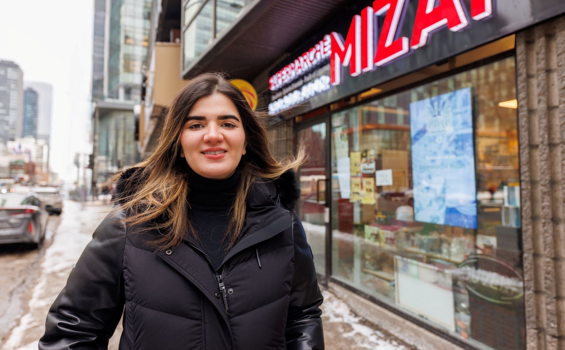 A woman stands outside a grocery store on a city street