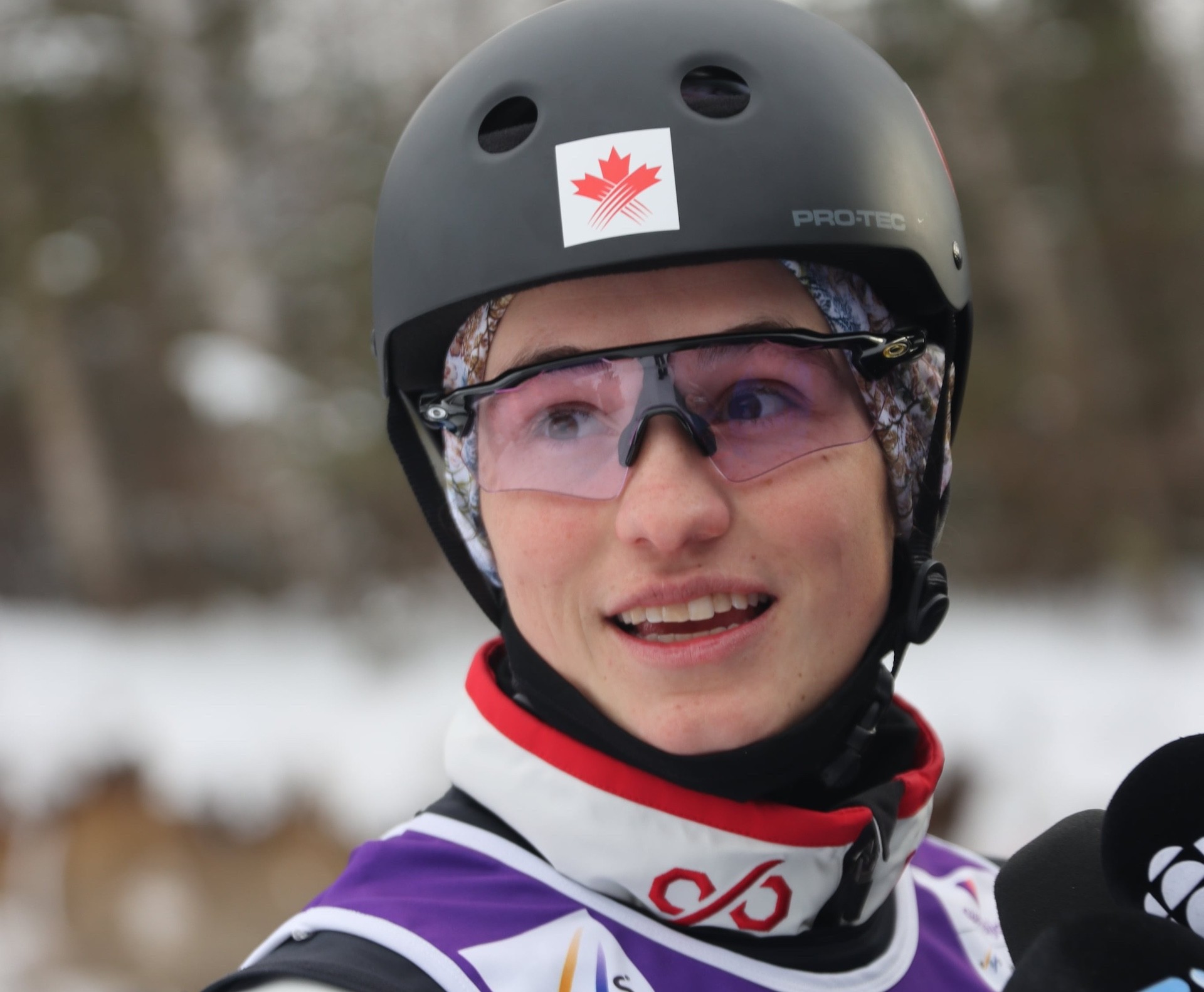 Head-and-shoulders portrait of a young female skier wearing a helmet and a competition bib