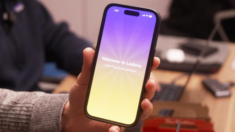 A hand holding a cellphone with the words, "Welcome to Lovado" on the screen