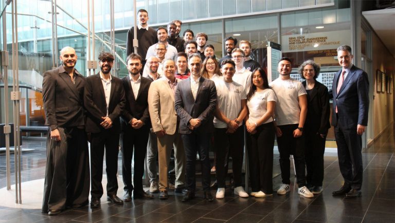 A group of people standing together in an atrium and smiling for the camera.