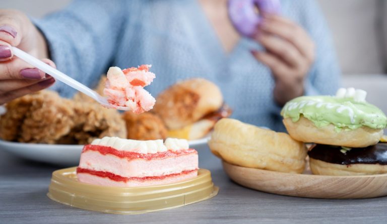 A blurred woman eats junk food