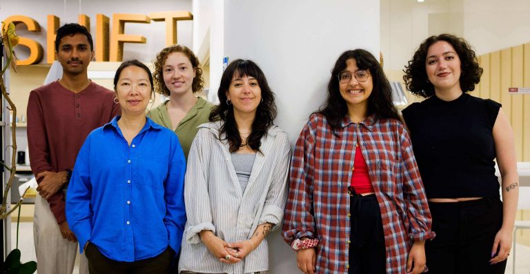 A group of people standing together in a line and smiling for the camera