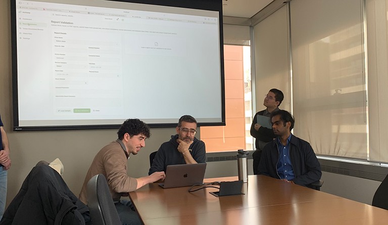 A group of men sitting at a table looking at a laptop