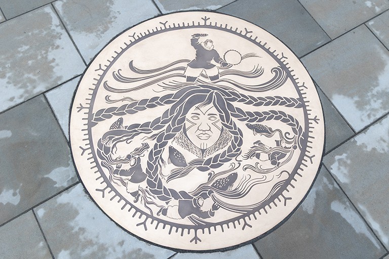 A bronze medallion artwork embedded in stone tiles