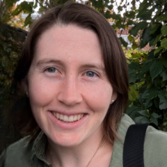Un portrait d'une jeune femme souriante, avec les cheveux bruns mi-longs