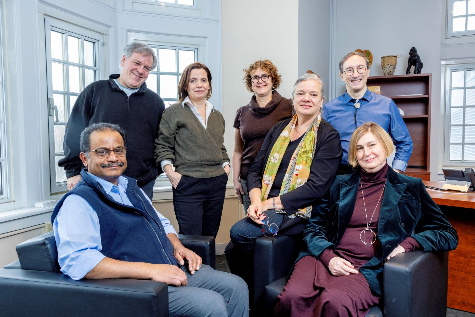 Sept personnes (trois hommes, quatre femmes) assises et debout ensemble en groupe, dans le bureau du doyen, regardant la caméra.