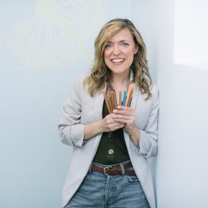 Woman smiling with colored pencils in her hands