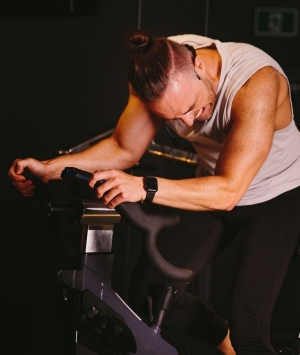 Un homme en débardeur s'entraîne pendant un cours de spinning.