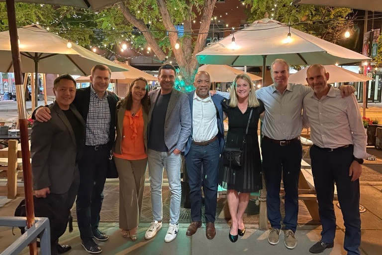 Un groupe de personnes se réunit et pose pour une photo en plein air à la terrasse d'un restaurant.